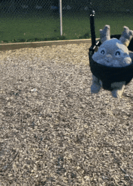 a stuffed animal is sitting in a swing at a park