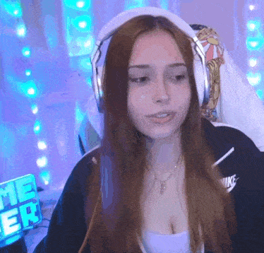 a woman wearing headphones and a necklace is sitting in front of a purple wall .