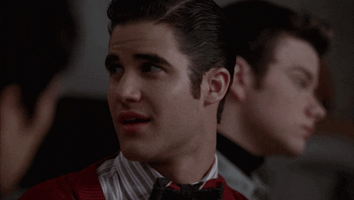 a man in a red shirt and bow tie is looking to the side