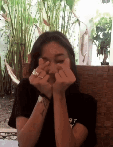 a woman making a heart shape with her hands while wearing a watch and a ring