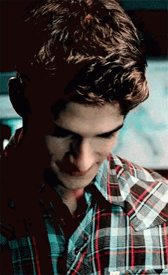 a young man wearing a plaid shirt looks down