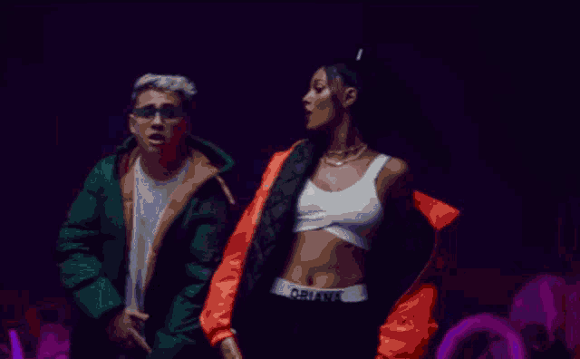 a man in a green jacket is pointing at a woman in a red jacket