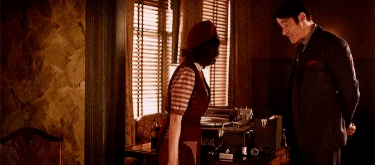 a man and a woman are standing next to each other in front of a window .