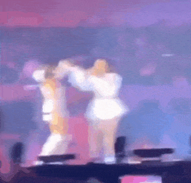 two women are dancing on a stage in a blurry photo .