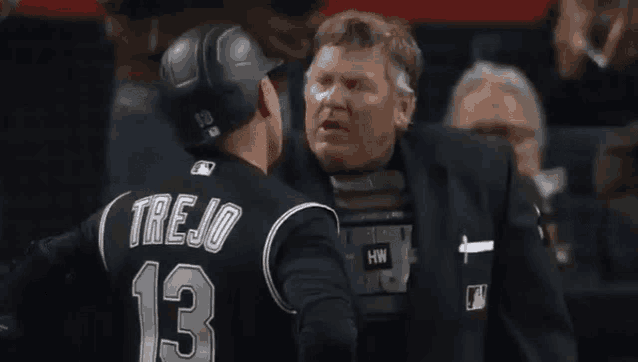 a man in a suit is talking to a baseball player wearing a number 13 jersey