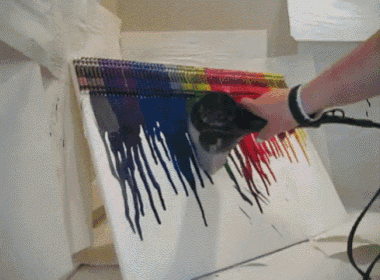 a person using a hair dryer to dry a painting of crayons on a canvas