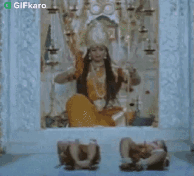 a woman is sitting in front of a statue of a deity .