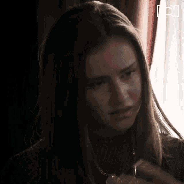 a woman in a dark room with the letter p on the bottom