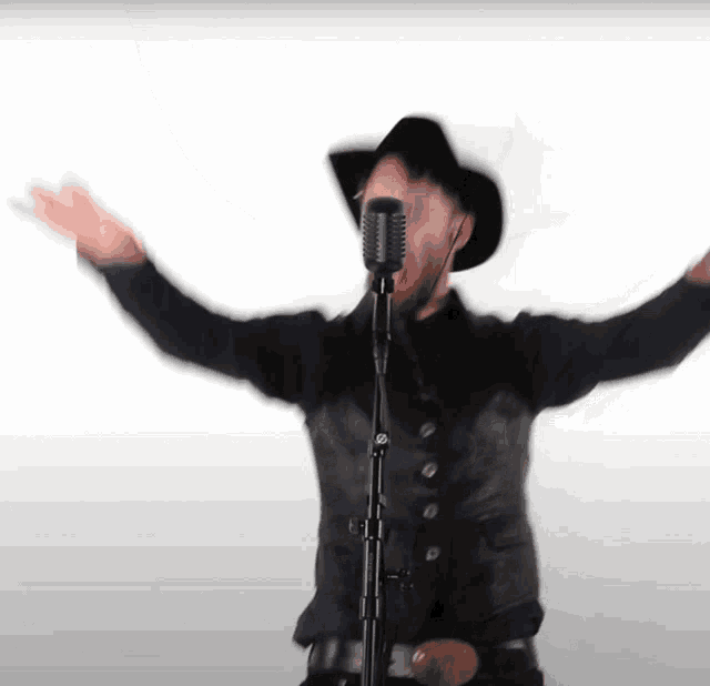 a man singing into a microphone with his arms outstretched