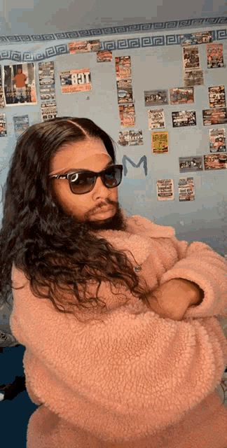 a woman with long hair and a beard wearing sunglasses and a pink jacket