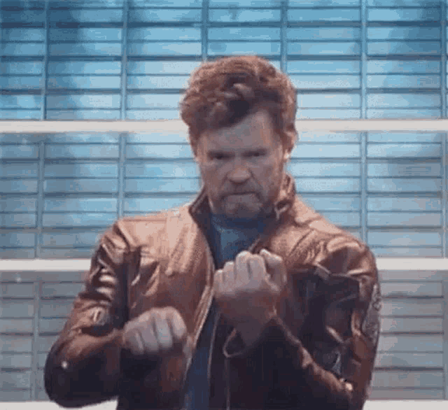 a man with a beard is wearing a leather jacket and making a funny face .