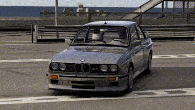 a silver bmw is parked in a parking lot near the ocean .