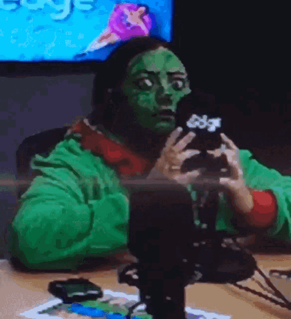 a person with a green mask on their face is sitting in front of a microphone with the word edge on it