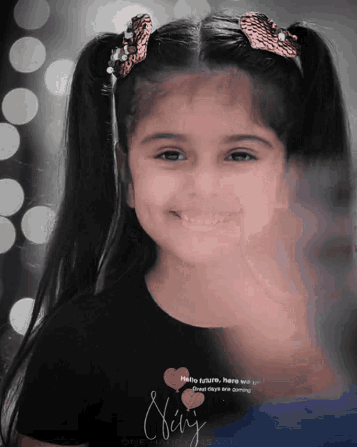 a little girl is smiling and wearing a black shirt that says ' shiny ' on it