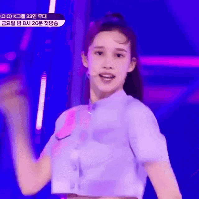 a woman in a purple crop top is dancing on a stage .