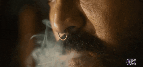 a man with a nose ring and a beard is smoking