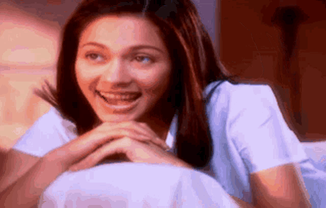 a woman in a white shirt is smiling with her hands folded