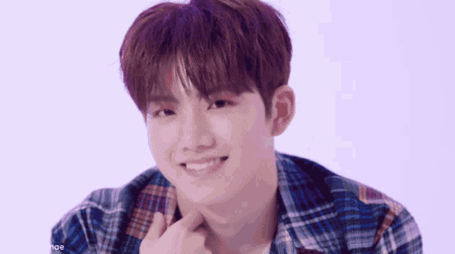 a close up of a young man wearing a plaid shirt smiling .