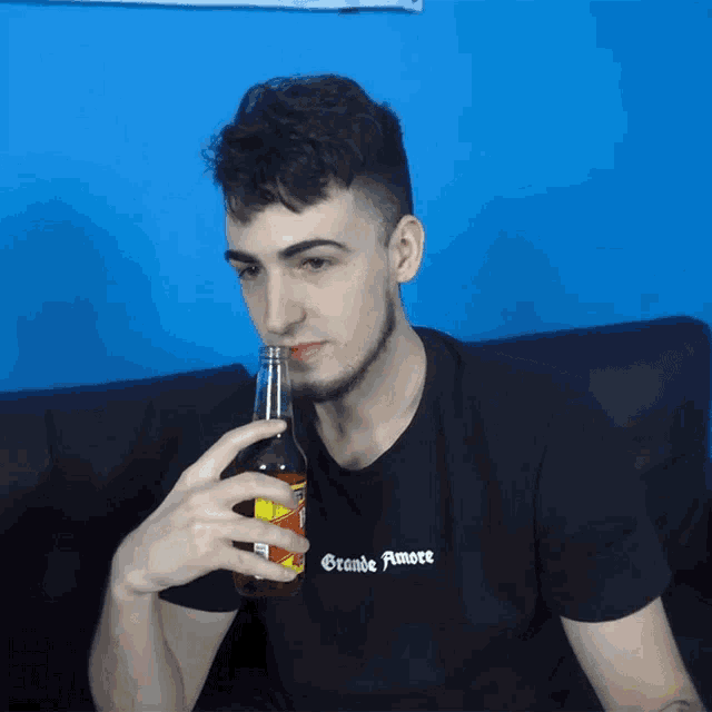a man drinking from a bottle with the word grande amore on his shirt