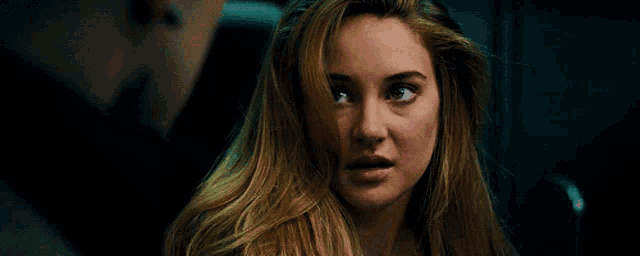 a close up of a woman 's face with a man in the background .