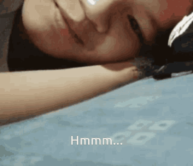 a close up of a person laying on a bed with the word hmm on the bottom right