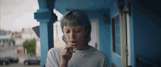 a woman with green hair is smoking a cigarette