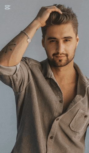 a man with a tattoo on his arm holds his hair