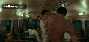 a group of people are sitting on a bus and fighting each other .
