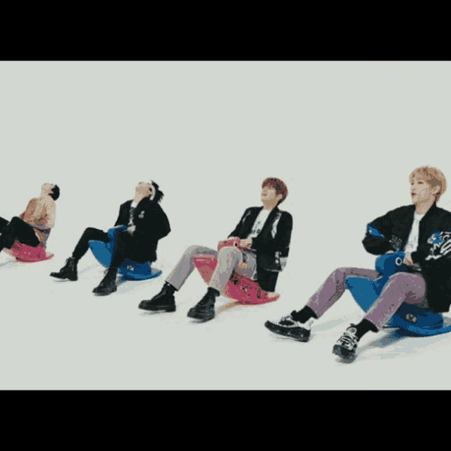 a group of young men are sitting on pink and blue rocking horses on a white background