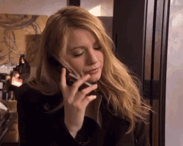 a woman is smoking a cigarette while talking on her cell phone