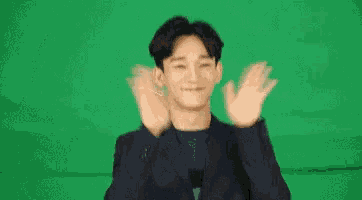 a man in a suit is smiling and pointing up
