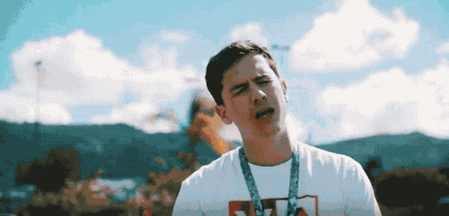 a young man wearing a fila shirt stands in front of a mountain