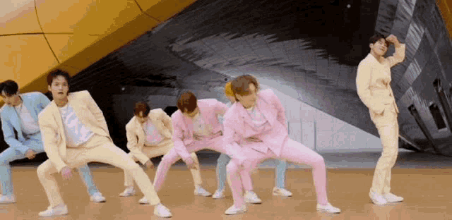 a group of men in suits are dancing together on a stage .
