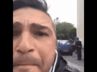 a man wearing a face mask is standing in front of a blue car