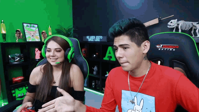 a man wearing a red shirt with a bunny on it is sitting next to a woman wearing green headphones