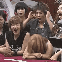 a group of people are sitting around a table with the word sbs on the wall behind them