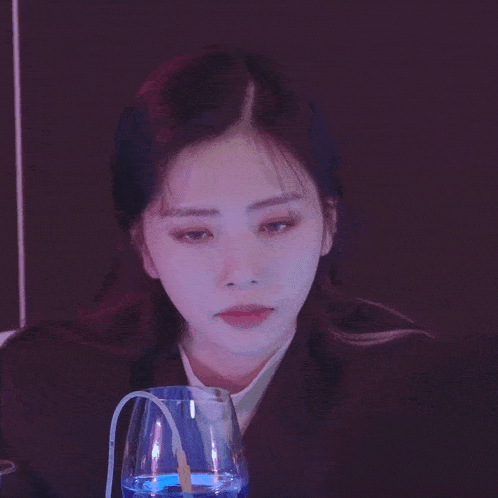 a woman laughs while holding a glass of blue liquid