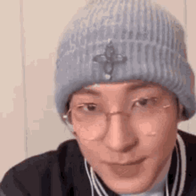 a man wearing a blue beanie and glasses is making a funny face .