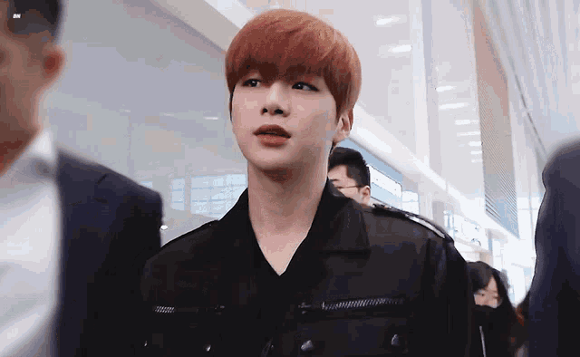 a young man with red hair is wearing a black jacket and a black shirt