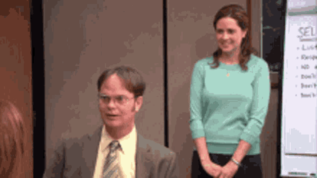 a man in a suit and tie sits next to a woman in a green shirt