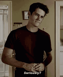 a man in a red t-shirt is standing in a room and says seriously .