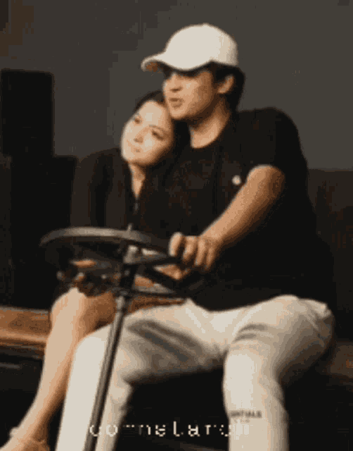 a man in a white hat sits next to a woman on a couch