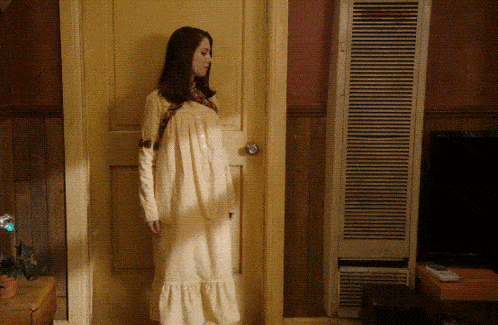 a woman in a white dress stands in front of a yellow door