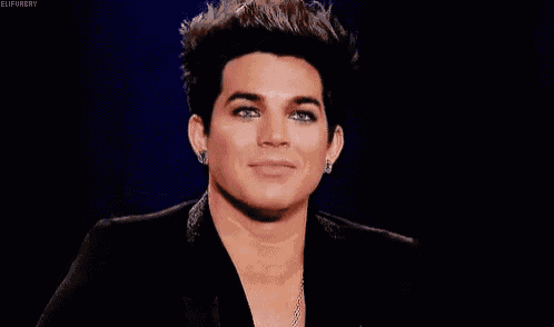 a close up of a man 's face with a black jacket and earrings .