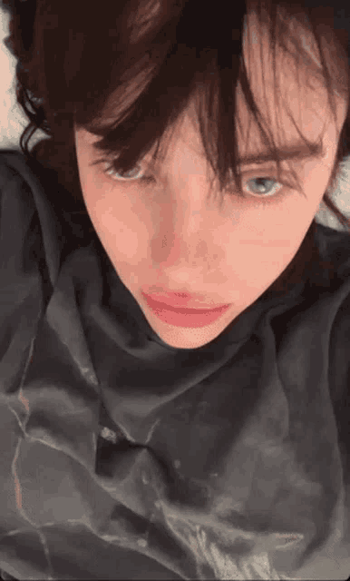 a close up of a person 's face with a gray shirt on .