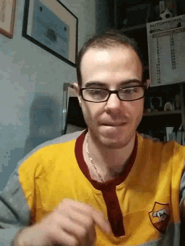 a man wearing glasses and a yellow roma shirt