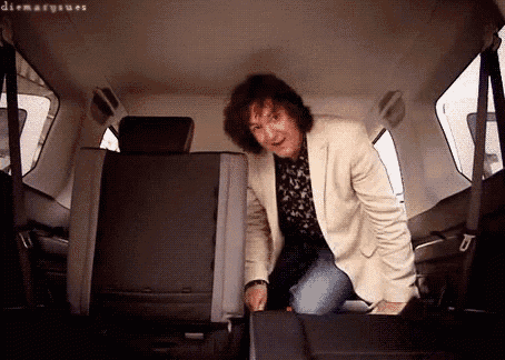 a man in a white jacket is standing in the back seat of a car