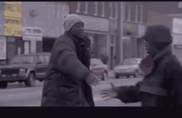 two men are hugging each other on a street in a city .