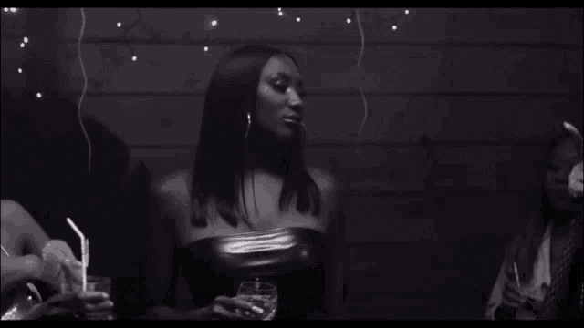 a woman in a black dress is holding a glass of water
