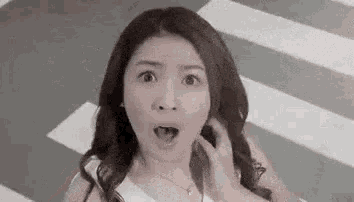 a woman with a surprised look on her face is standing in front of a crosswalk .